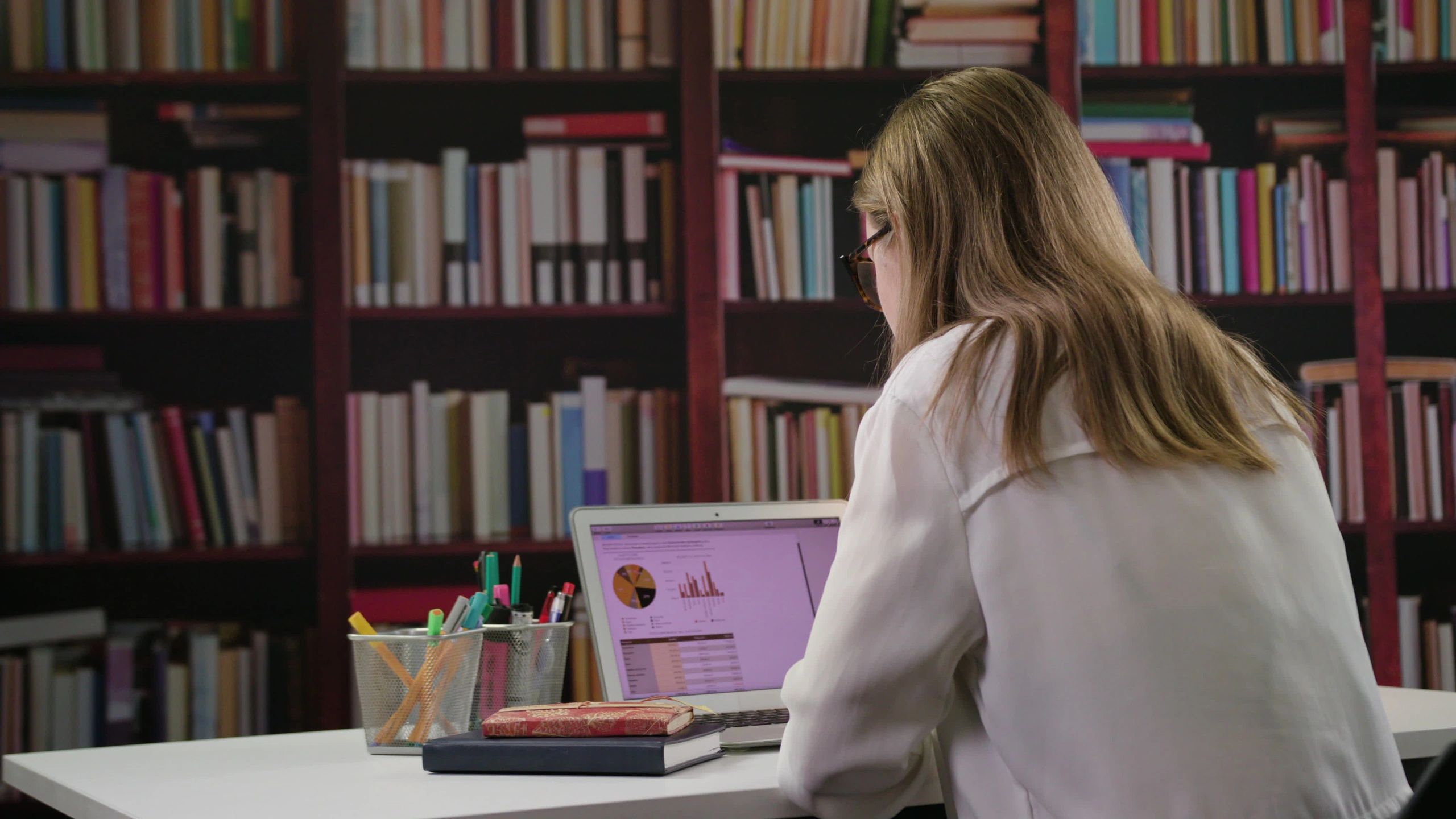 Researcher working on a laptop in a library